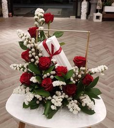 a bouquet of roses and white flowers on a chair with a red ribbon tied around it