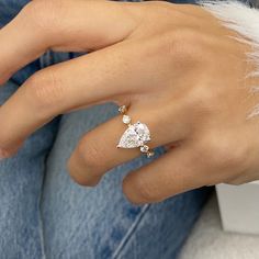 a woman's hand with a diamond ring on top of her finger and the other hand holding an engagement ring