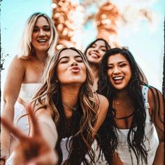 group of women taking selfies with their hands in the air and smiling at camera