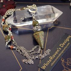 a necklace with some charms on it sitting next to a crystal block and a book