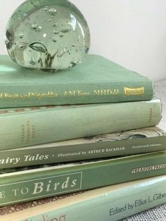 a stack of books sitting on top of each other next to a glass vase filled with water