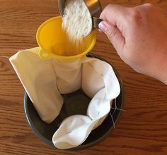 a person pouring something into a cup on top of a wooden table with napkins