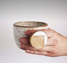 a hand holding a white and brown cup