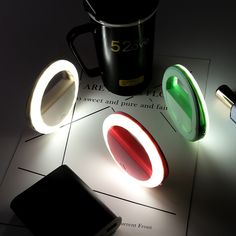 three different colored lights on top of a table next to a coffee cup and cell phone