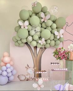 a table topped with balloons and a tree filled with lots of different types of balloons