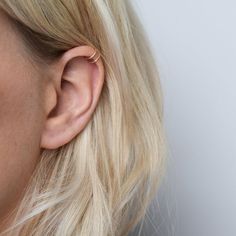 a close up of a woman's ear and nose wearing gold earrings with diamond accents