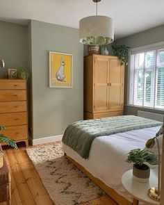 a bed room with a neatly made bed next to a window and a wooden dresser