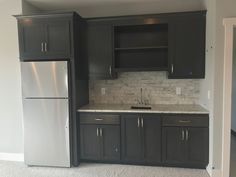 an empty kitchen with black cabinets and silver appliances