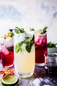 three glasses filled with different types of drinks and garnished with mint, lime, and lemon