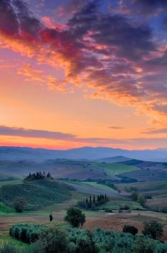 the sun sets over rolling hills and fields