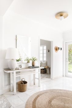 a living room with white walls and flooring next to a large mirror on the wall