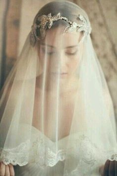 a woman wearing a wedding veil and holding a cell phone in her hand while looking down