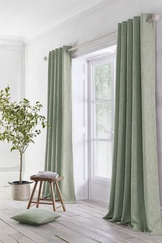 a living room with green curtains and a potted plant