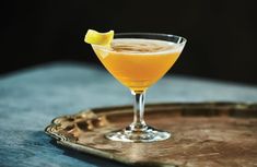 a glass filled with orange juice and garnished with a lemon wedge on a tray