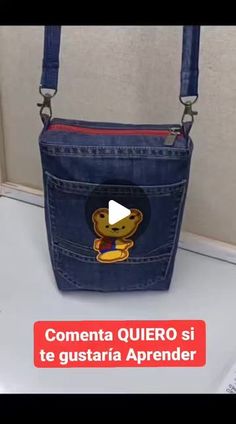 a blue purse with a cartoon bear on the front and side pocket, sitting on top of a toilet