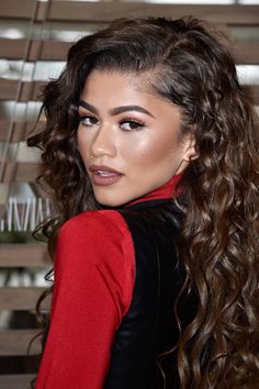 a woman with long curly hair wearing a red top