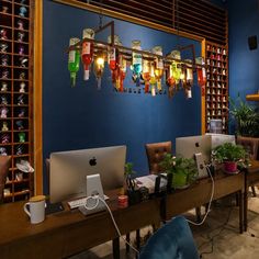 two laptops are sitting on a desk in front of a wall with many bottles