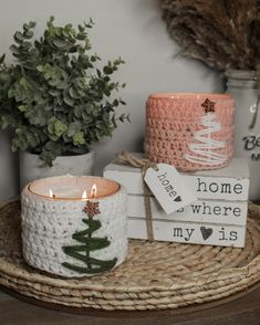 two crocheted candles sitting on top of a wicker tray next to a potted plant