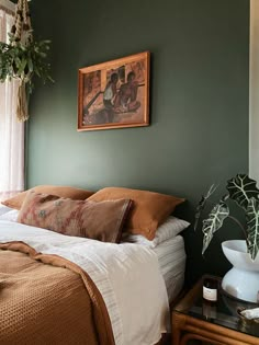 a bed sitting in a bedroom next to a window with green walls and pillows on top of it