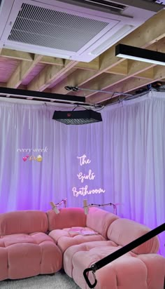 a pink couch sitting on top of a carpet covered floor next to a white curtain