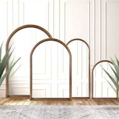 three wooden archs with plants in them on a wood floor next to a white wall