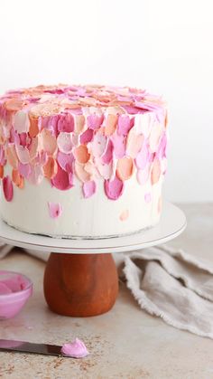 a white cake with pink icing and hearts on it, sitting on a plate