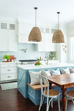 a kitchen with white cabinets and blue island in the center, surrounded by wicker pendant lights