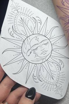 a woman's hand holding up a paper cutout with the sun and moon on it