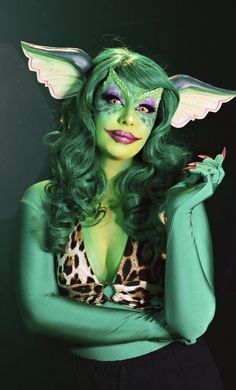 a woman with green hair and makeup is posing for the camera wearing a cat costume