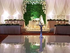 an elegant wedding setup with white flowers and greenery on the wall behind the table