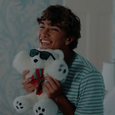 a young man holding a stuffed panda bear in his right hand and smiling at the camera