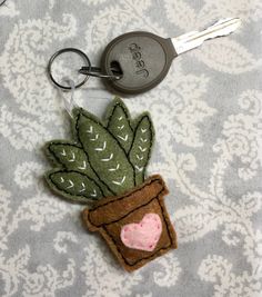 a keychain with a potted plant on it and a heart in the middle