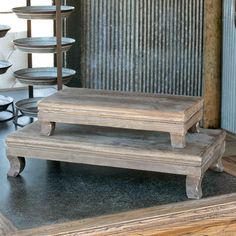 three wooden benches sitting next to each other in front of a metal rack with plates on it