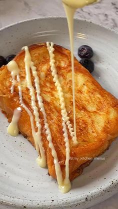 a piece of french toast is being drizzled with butter and blueberries