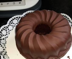 a chocolate bundt cake sitting on top of a white plate with a lace doily