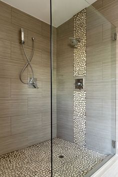 an image of a walk in shower with pebbles on the wall and tile flooring