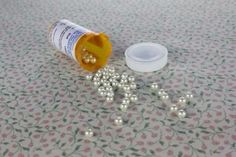 an open medicine bottle sitting on top of a table next to some balls and beads