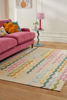 a living room with a pink couch and colorful rug