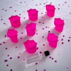 a bottle filled with pink plastic cups next to confetti