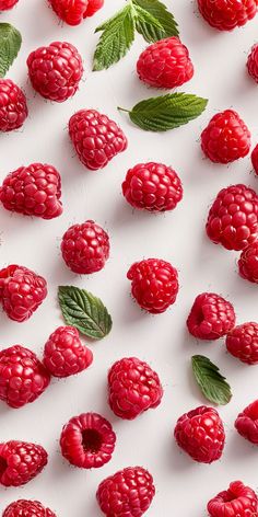 raspberries and leaves on a white surface