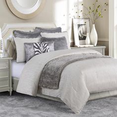 a white bed sitting in a bedroom next to a dresser and mirror with flowers on it