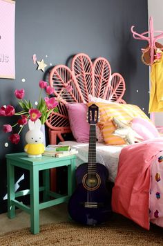 a bedroom with a guitar on the bed next to a table and flowers in vases