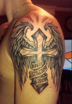 a cross with angel wings and ribbons on the shoulder is shown in this tattoo design