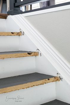 the bottom part of a stair case that has been painted white with brown tape on it