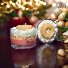 a candle that is sitting on a table next to some cookies and christmas decorations with lights in the background