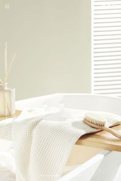 a wooden table topped with a white bath tub next to a toothbrush and soap dispenser