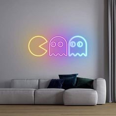 two neon ghost wall decals on the wall above a couch in a living room