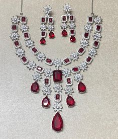 Ruby Necklace features a striking red stone and American diamond accents, inspired by Sabyasachi designs.  The intricate craftsmanship and luxurious look make it a perfect statement set for brides. Ideal for an Indian wedding, this elegant piece is a memorable gift for the bride. *𝐏𝐑𝐎𝐃𝐔𝐂𝐓 𝐃𝐄𝐓𝐀𝐈𝐋* * Material: Brass * Plating: White Rhodium Plated * Stone: Ruby And Diamond *𝐃𝐈𝐌𝐄𝐍𝐒𝐈𝐎𝐍𝐒* *𝐍𝐞𝐜𝐤𝐥𝐚𝐜𝐞* * 𝐖𝐞𝐢𝐠𝐡𝐭: 102 gm  * Drop 𝐋𝐞𝐧𝐠𝐭𝐡: 8 Inches * 𝐖𝐢𝐝𝐭𝐡: 4.3 Luxury Ruby Necklaces For Festive Season, Luxury Exquisite Ruby Necklace, Red Ruby Necklace For Festive Occasion, Red Ruby Necklace For Celebration, Elegant Red Necklace For Festive Occasions, Red Jeweled Bridal Necklace For Wedding, Formal Ruby Necklaces With Stone Setting, Traditional Red Jewelry Sets With Stones, Formal Ruby Necklace With Stone Setting