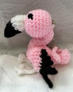 a small crocheted stuffed animal is sitting on a white cloth with a keychain