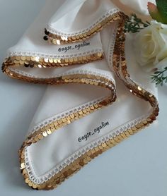 three pairs of shoes with gold sequins on them and white flowers in the background